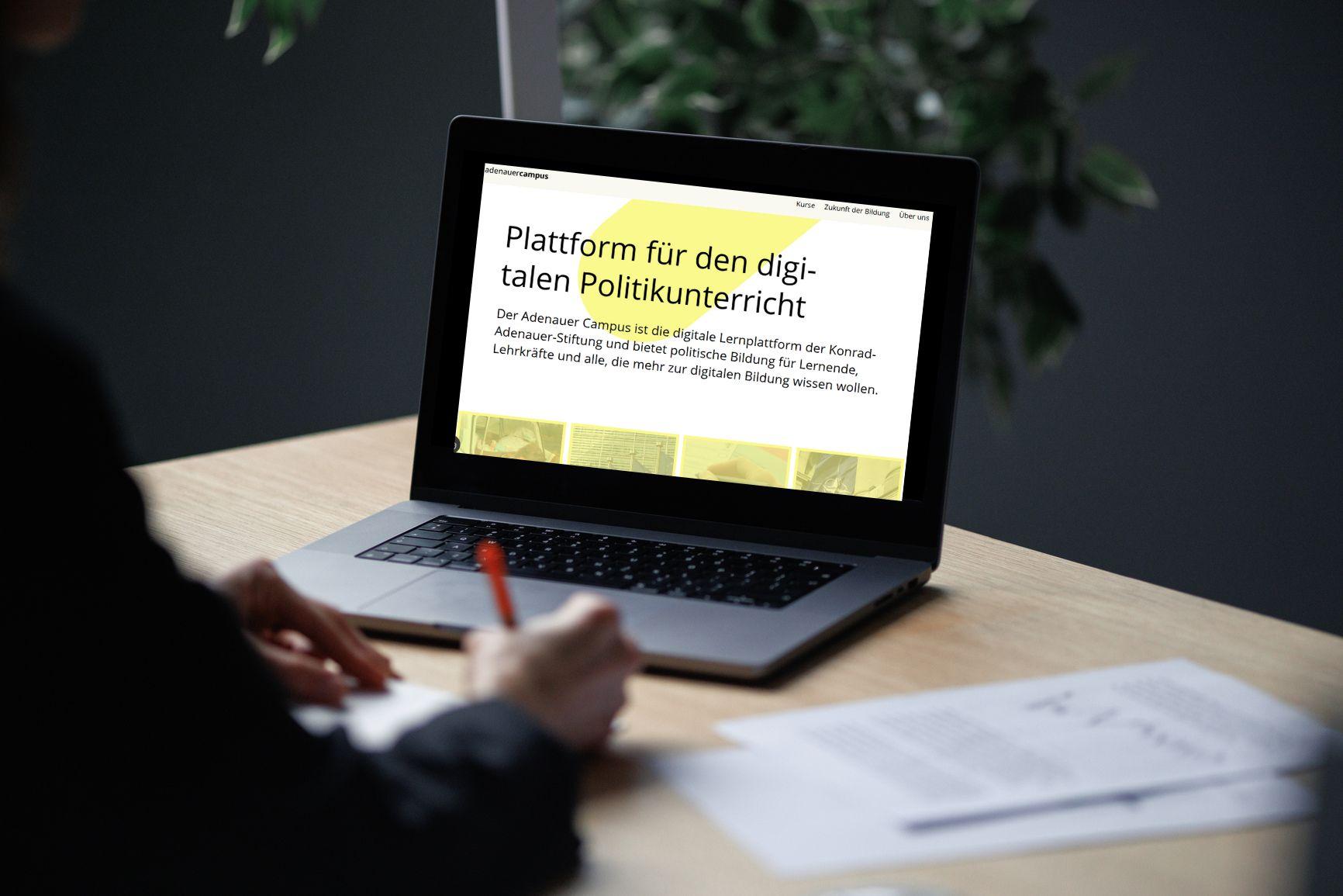 Ein Computer auf einem Arbeitsblatt, eine Hand davor
